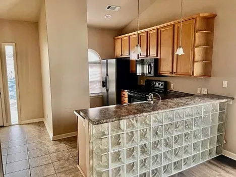 A kitchen with stainless steel appliances , wooden cabinets and a glass block counter.