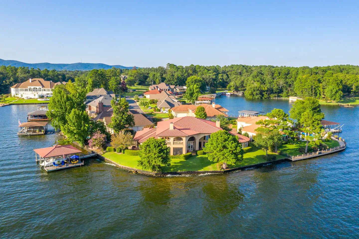 An aerial view of a house on a small island in the middle of a lake.