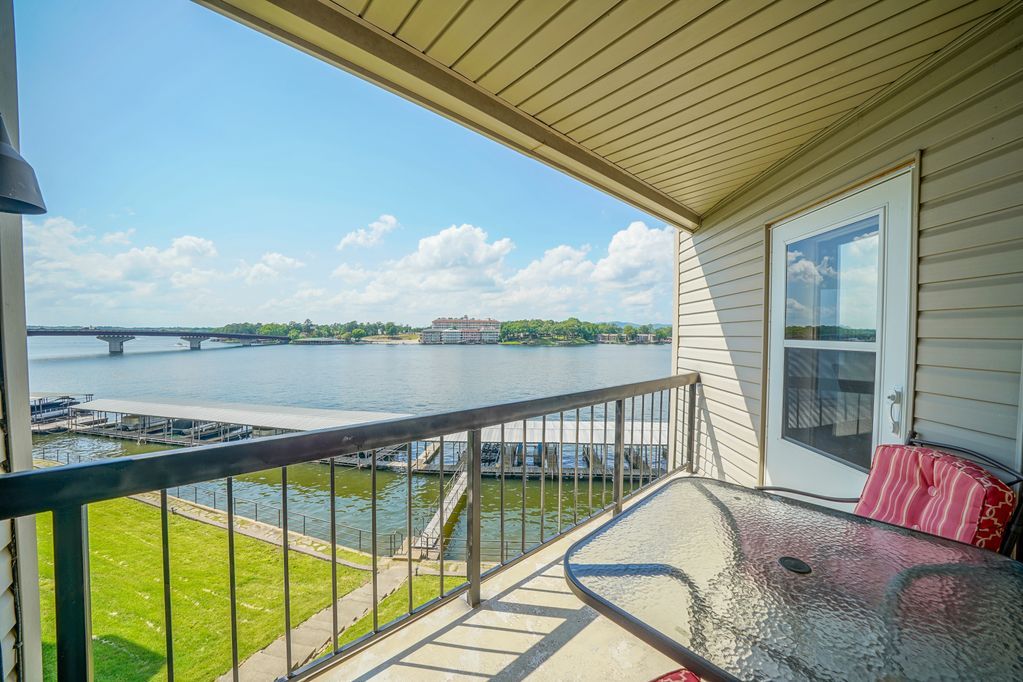 A balcony with a table and chairs overlooking a body of water.