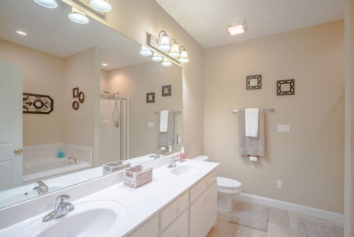 A bathroom with two sinks , a toilet , and a large mirror.