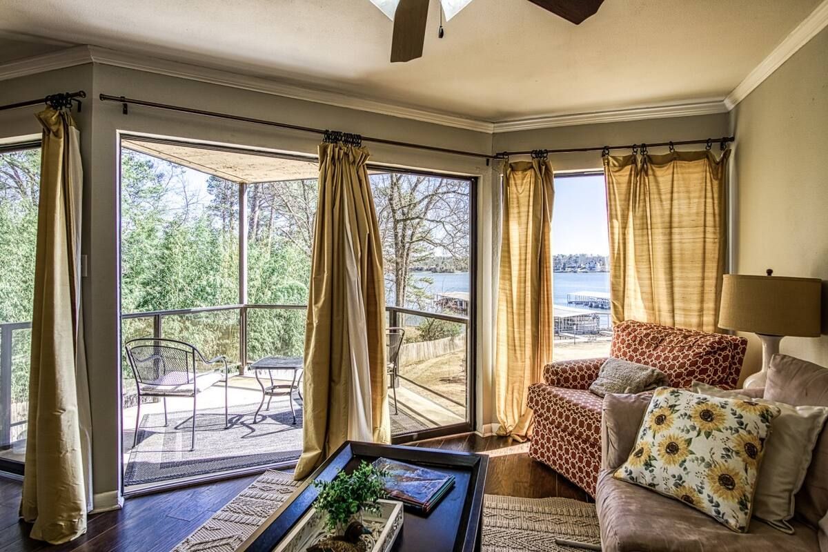 A living room with a lot of windows and a view of a lake.