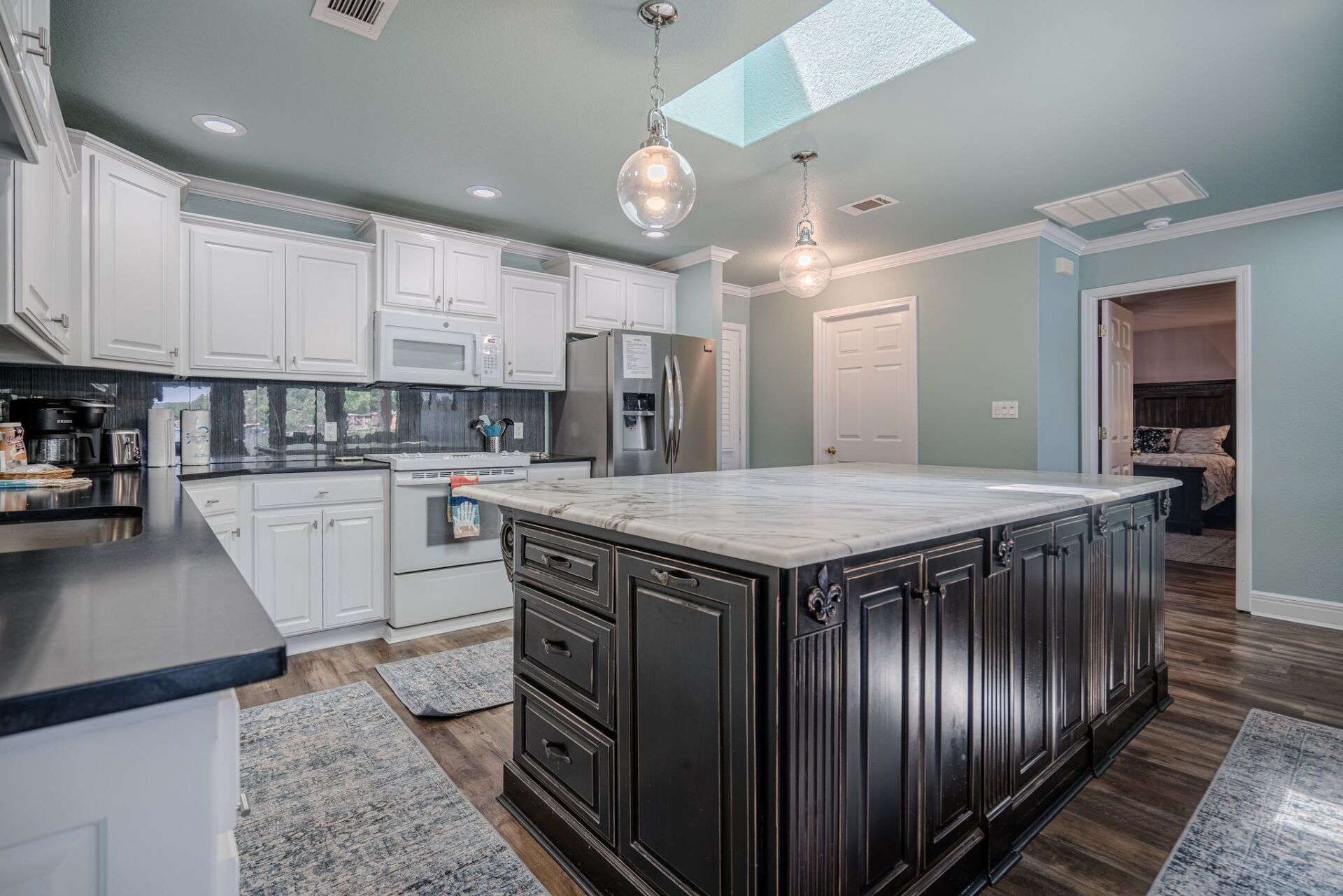 A kitchen with a large island in the middle and a skylight on the ceiling.