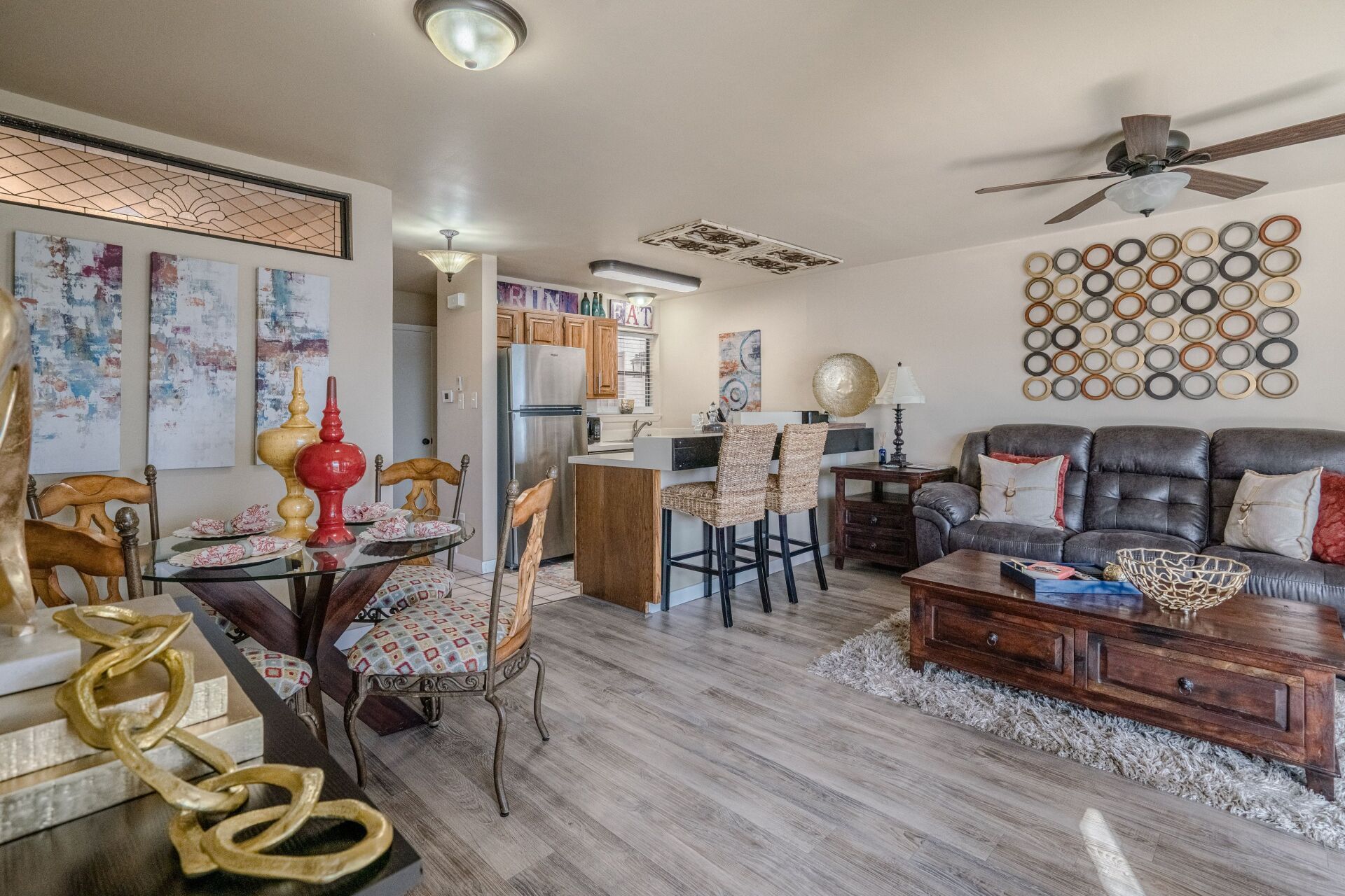 A living room with a couch , table , chairs and a ceiling fan.