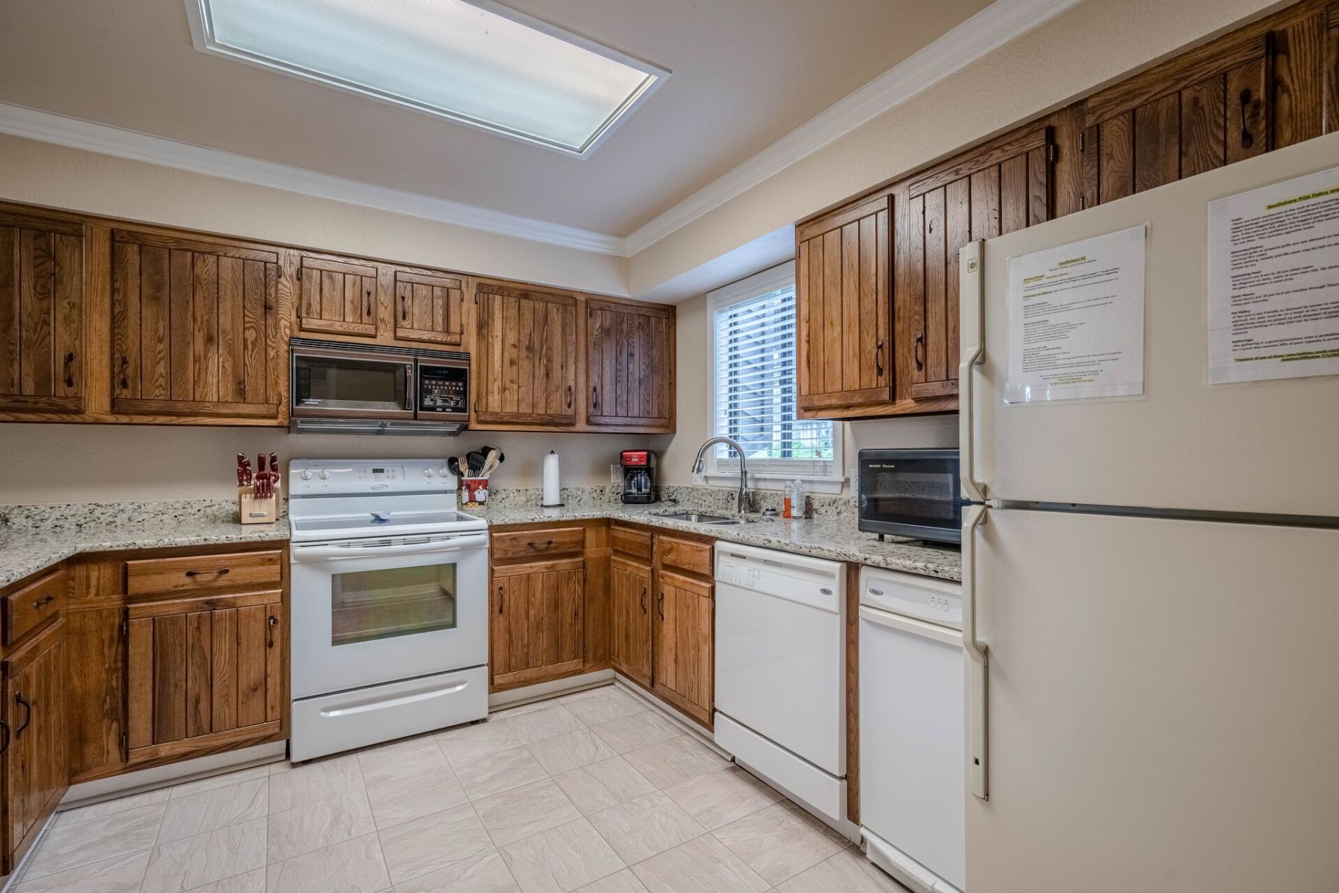 A kitchen with wooden cabinets , white appliances , and a refrigerator.