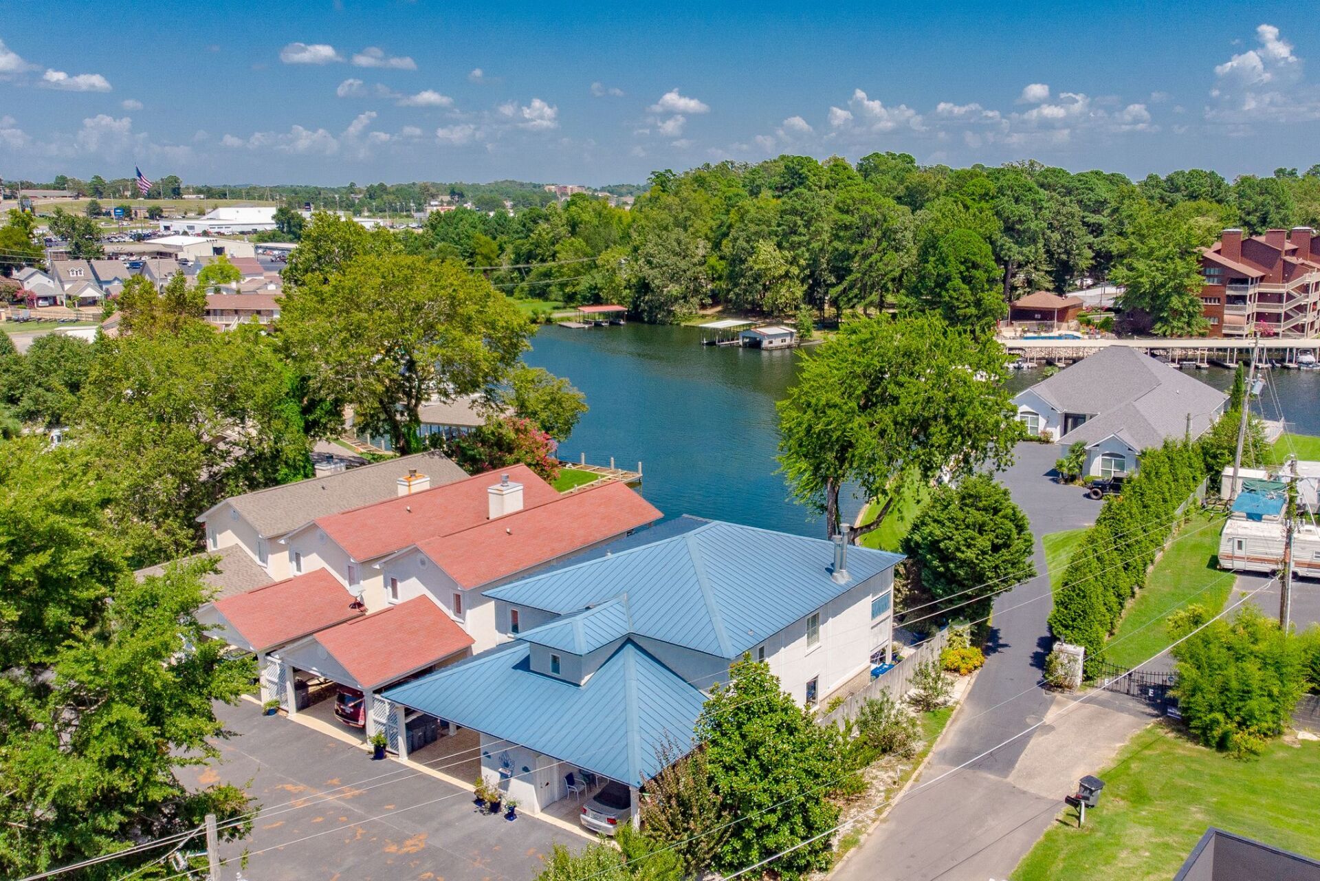 An aerial view of a house next to a lake surrounded by trees.