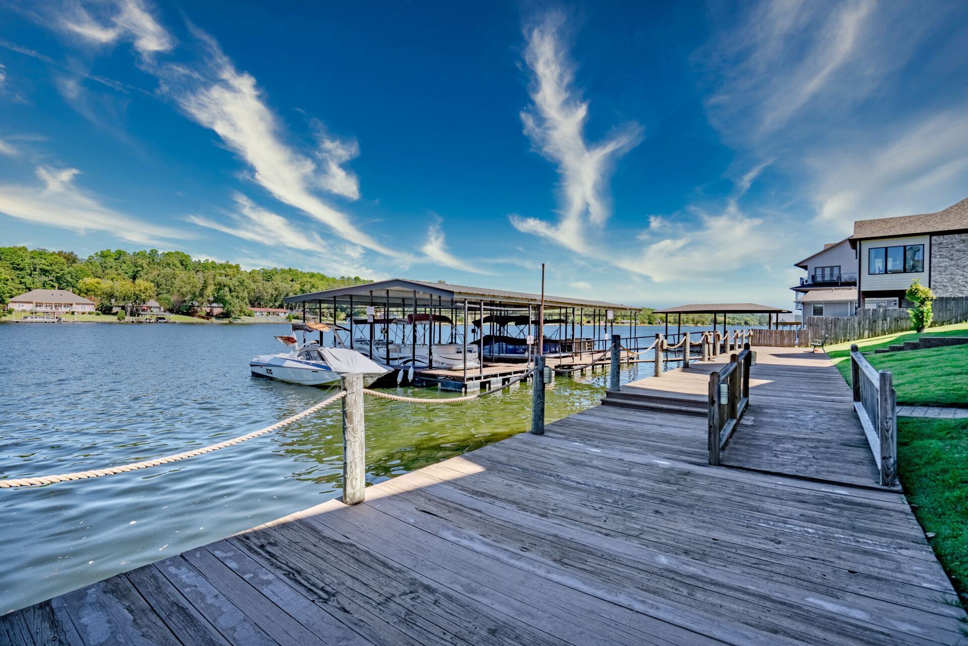 A dock with boats docked in the water and a house in the background.