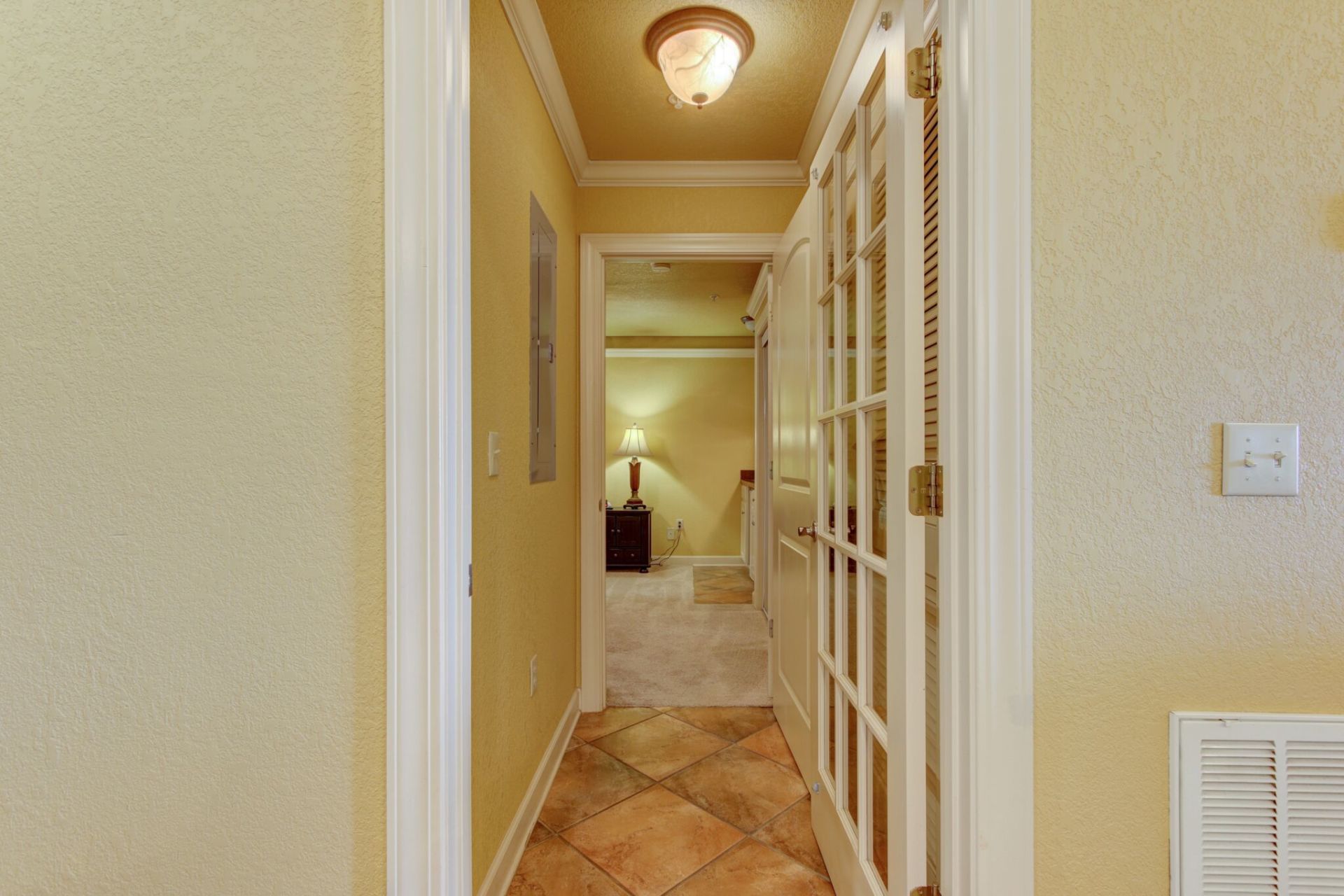 A hallway leading to a bedroom with a lamp on the wall