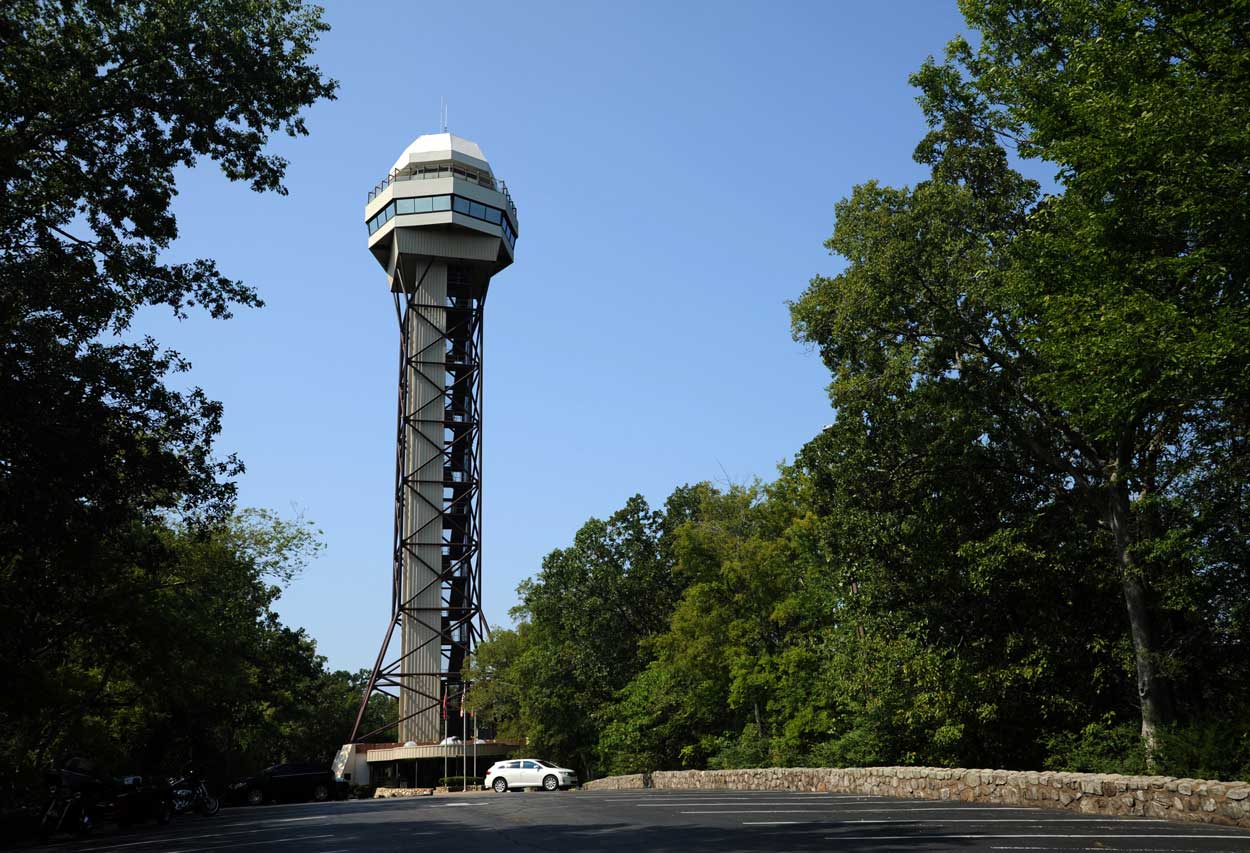 A tall tower is surrounded by trees on a sunny day