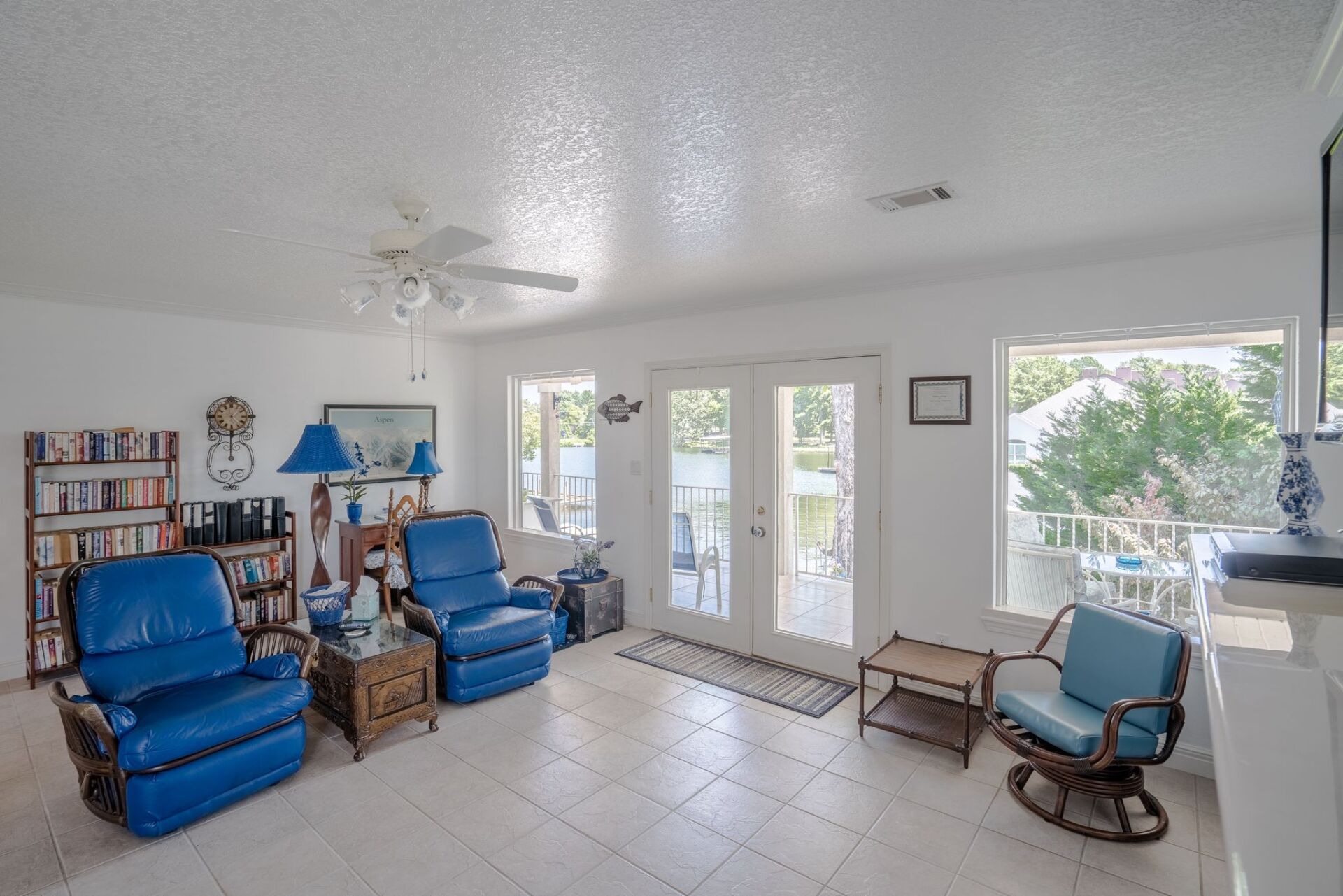 A living room with blue furniture and a ceiling fan.