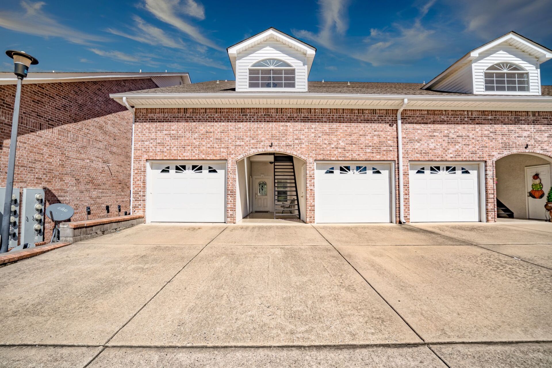 A brick house with three garage doors and a concrete driveway.