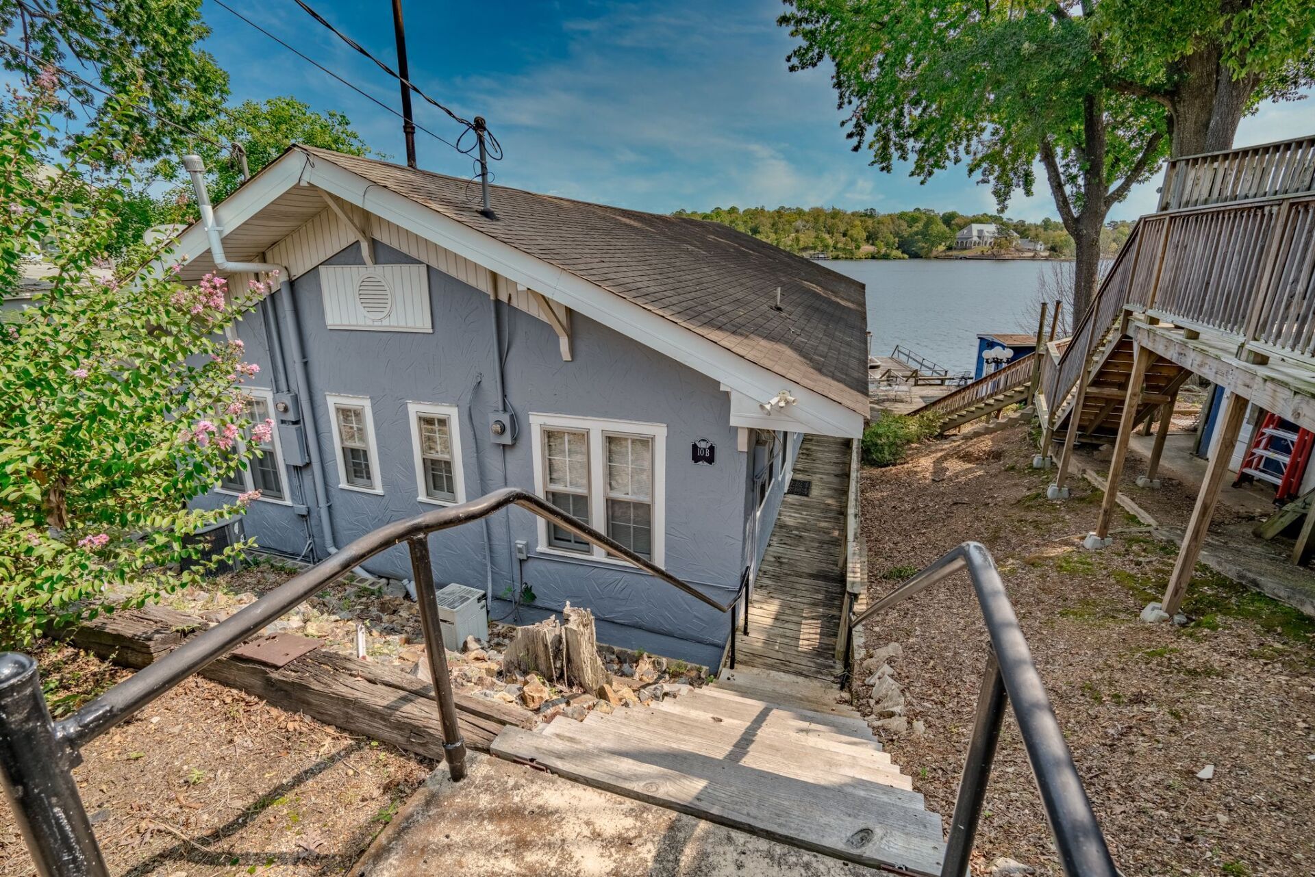 A house with stairs leading up to it and a lake in the background.