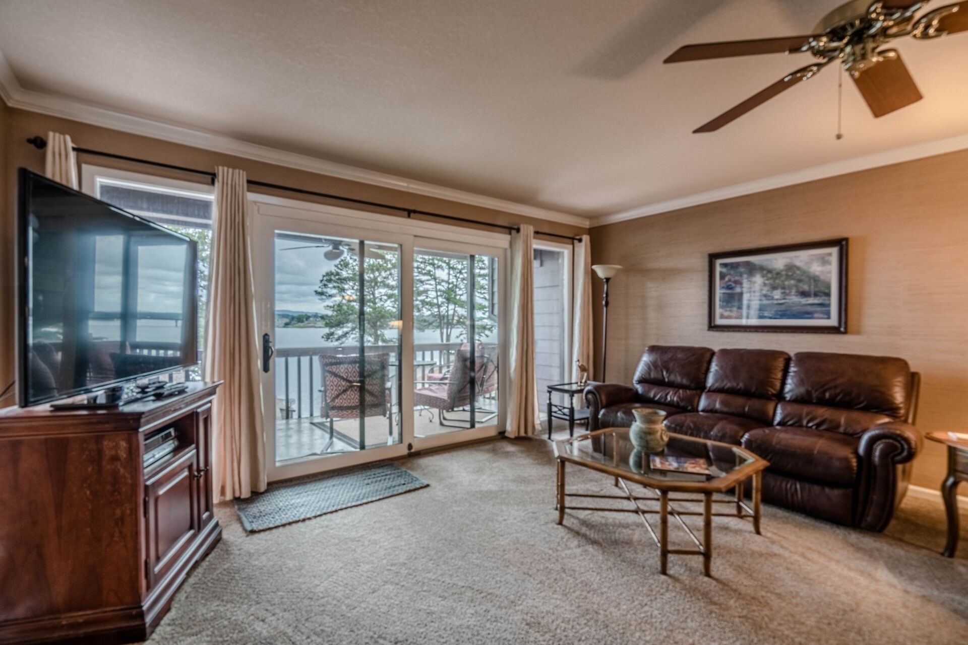 A living room with a couch , coffee table , television and ceiling fan.