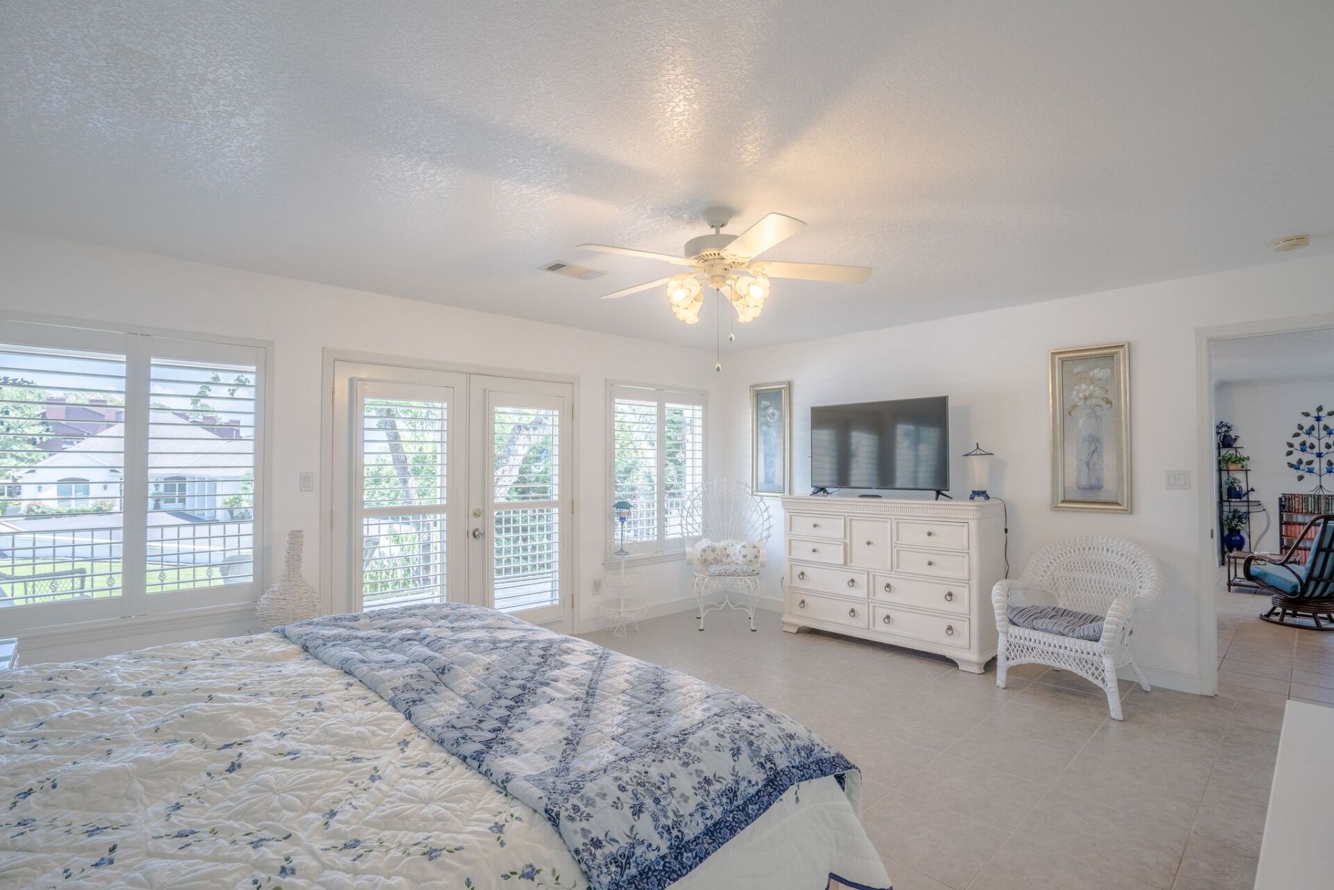 A large bedroom with a king size bed , dresser , chair and television.