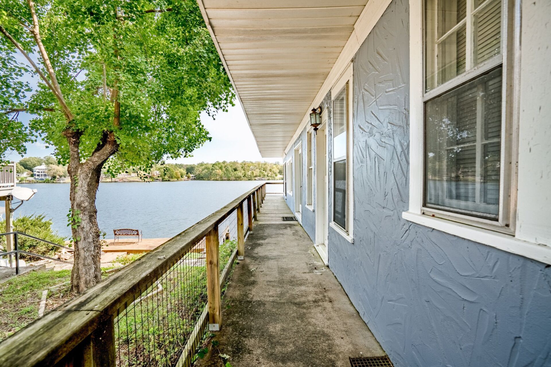 A blue house with a balcony overlooking a lake.