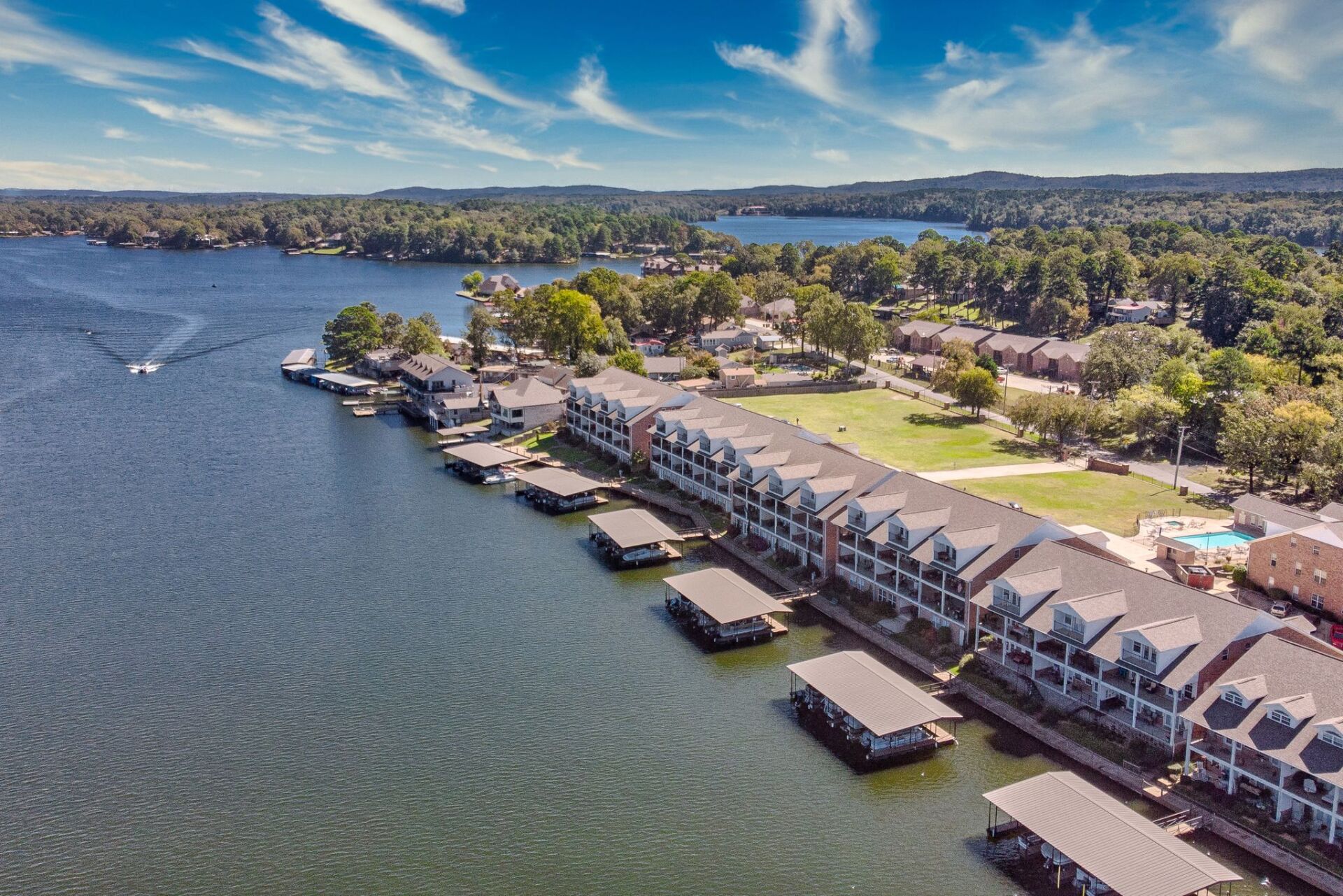 An aerial view of a lake with a row of houses on the shore.
