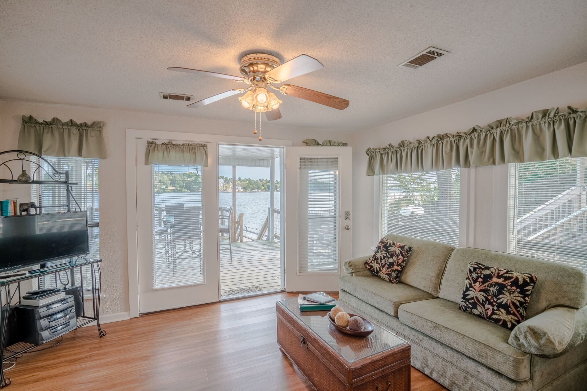 A living room with a couch , table , television and ceiling fan.
