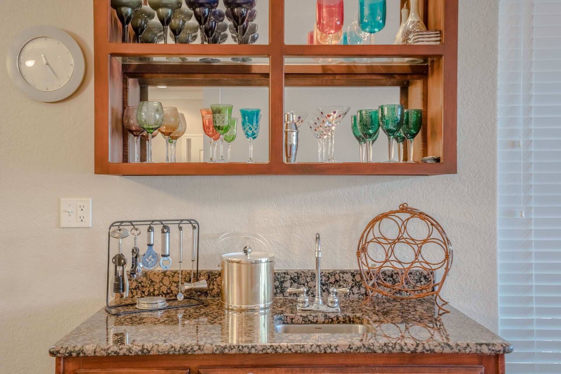 A kitchen counter with a shelf full of wine glasses