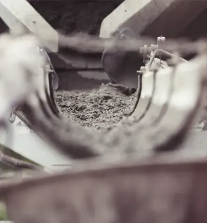 A black and white photo of a person pouring concrete into a pipe.