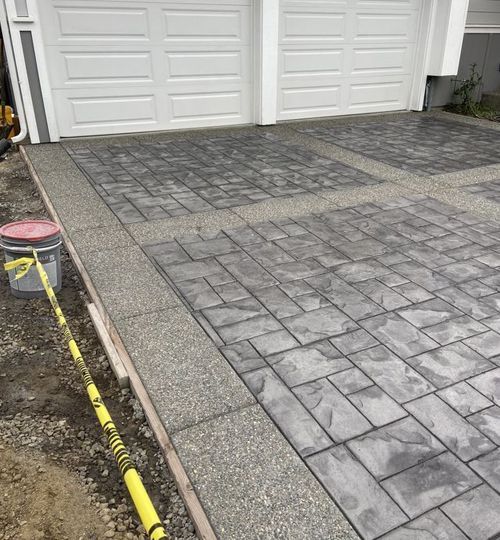 A stamped concrete driveway is being built in front of a garage door.