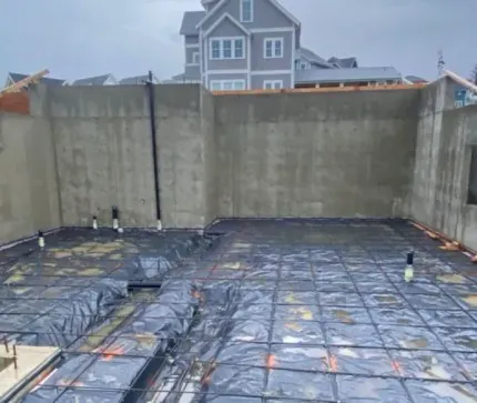 A concrete basement under construction with a house in the background