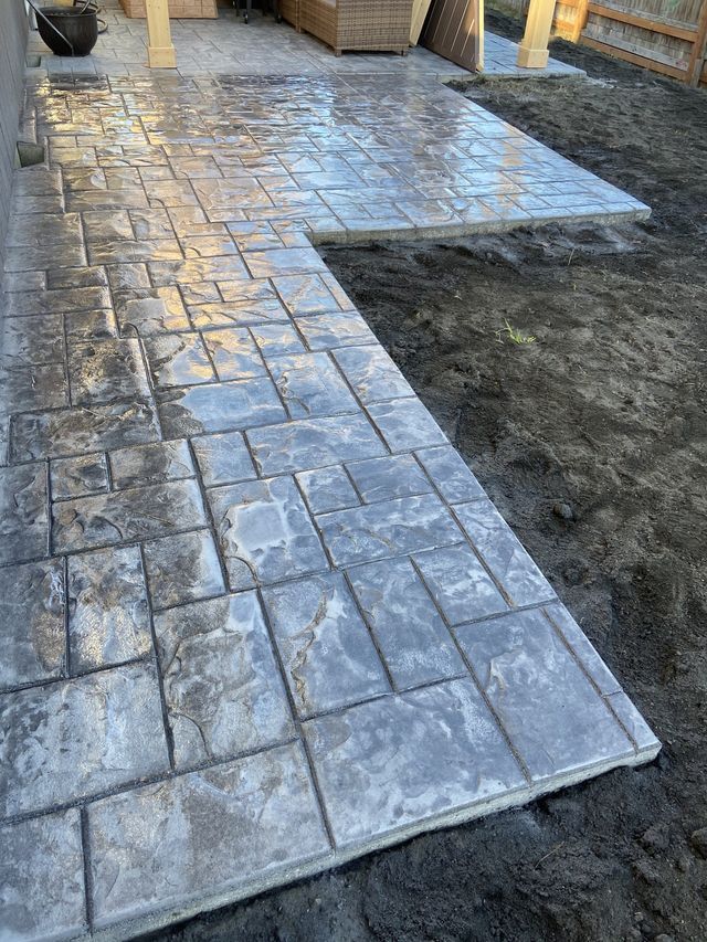 A concrete walkway is being built in a backyard.