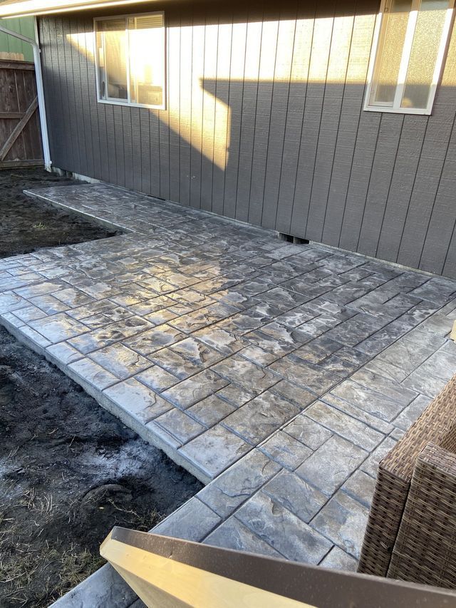 A patio with a chair and a couch in front of a house.