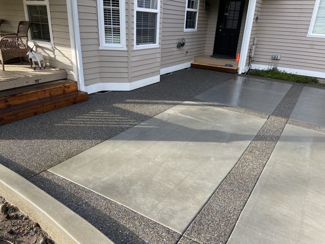 A concrete driveway in front of a house with a black door