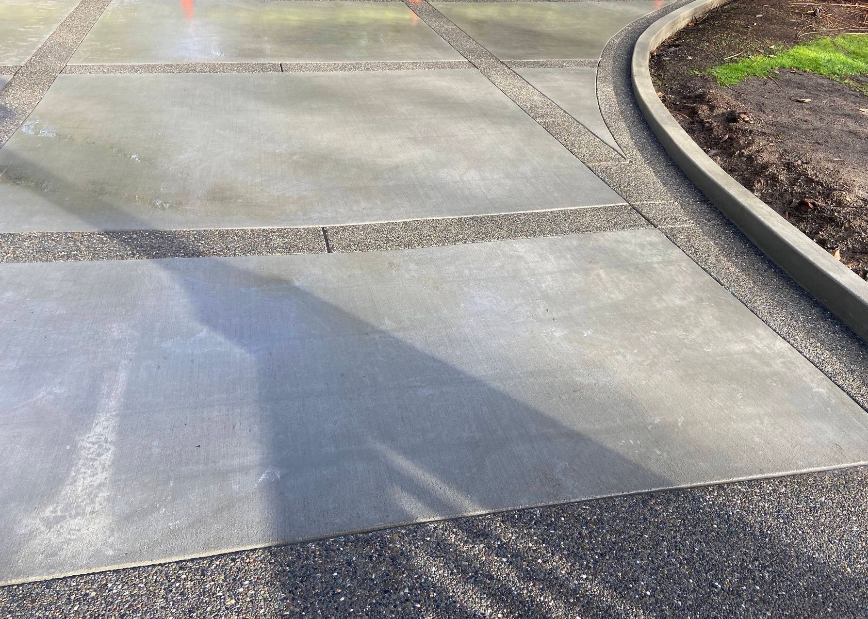 A close up of a concrete driveway with a curb.