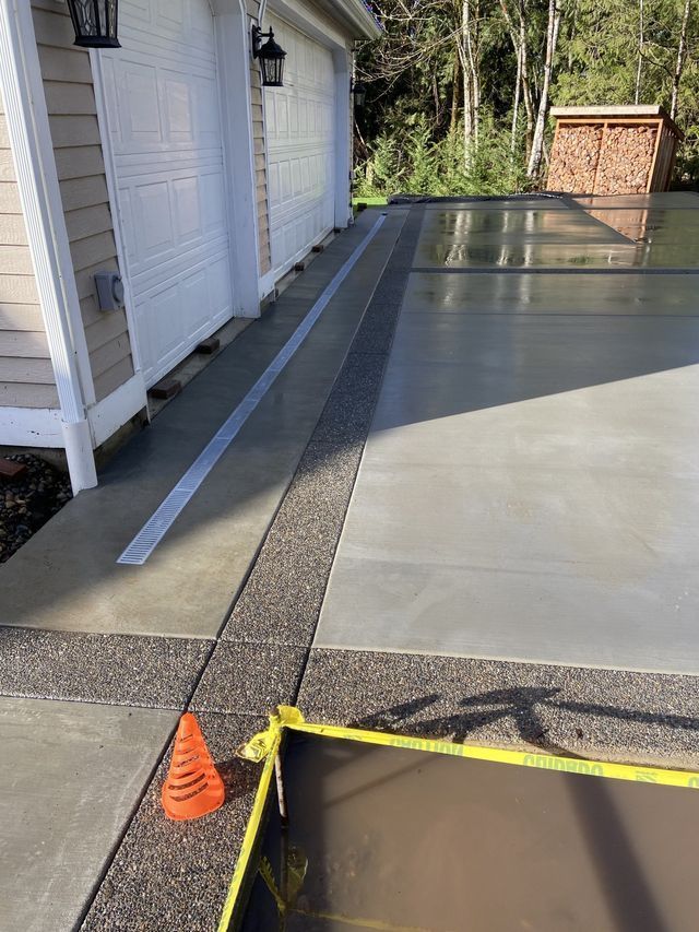 A concrete driveway with a cone and a yellow tape.