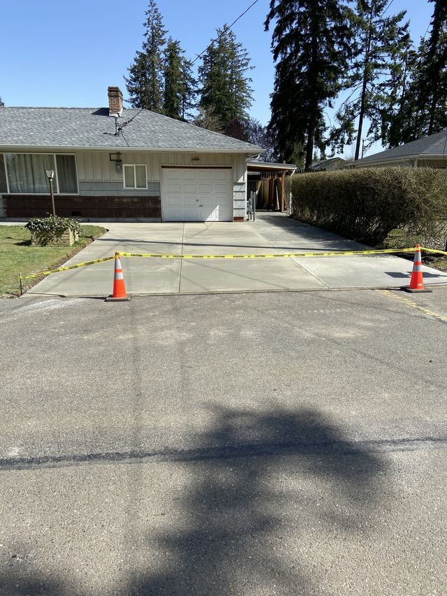 A driveway with two orange cones in front of a house