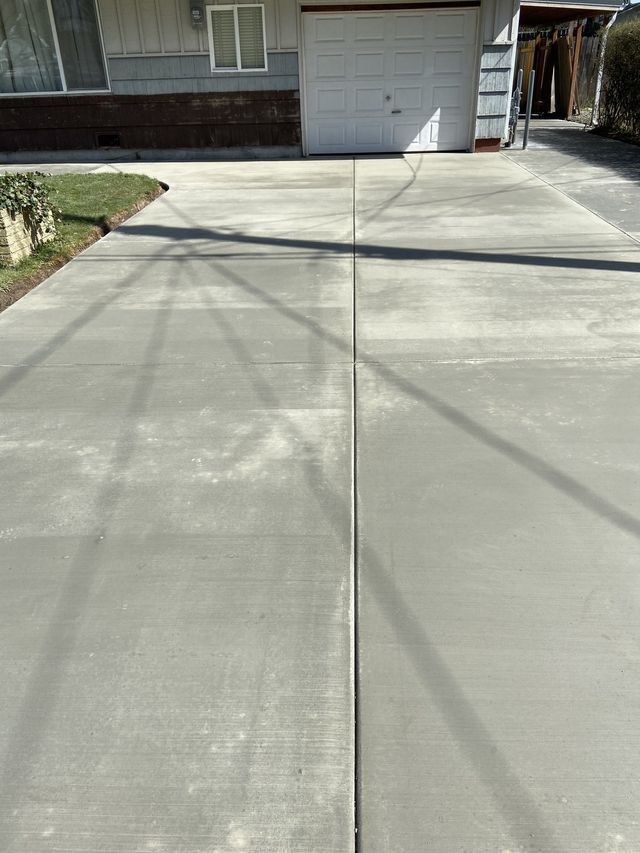 A concrete driveway in front of a house with a garage door.
