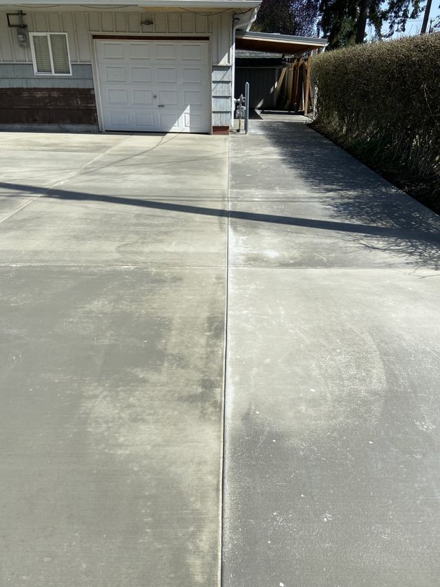 A concrete driveway leading to a house with a garage.