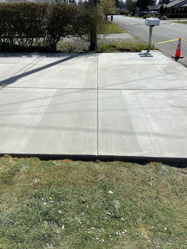 A concrete driveway with a mailbox on the side of the road.