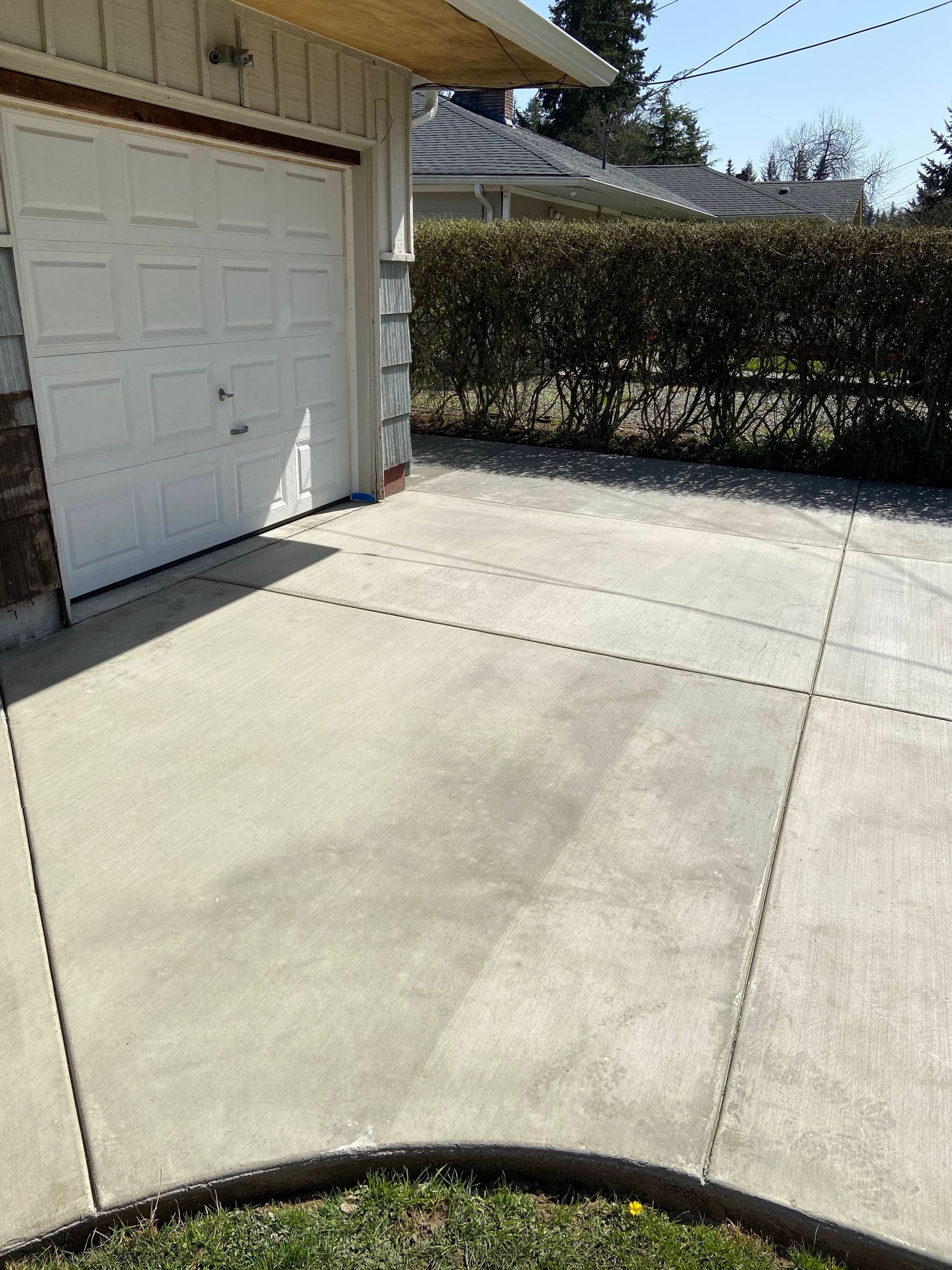 A concrete driveway leading to a garage with a white garage door.