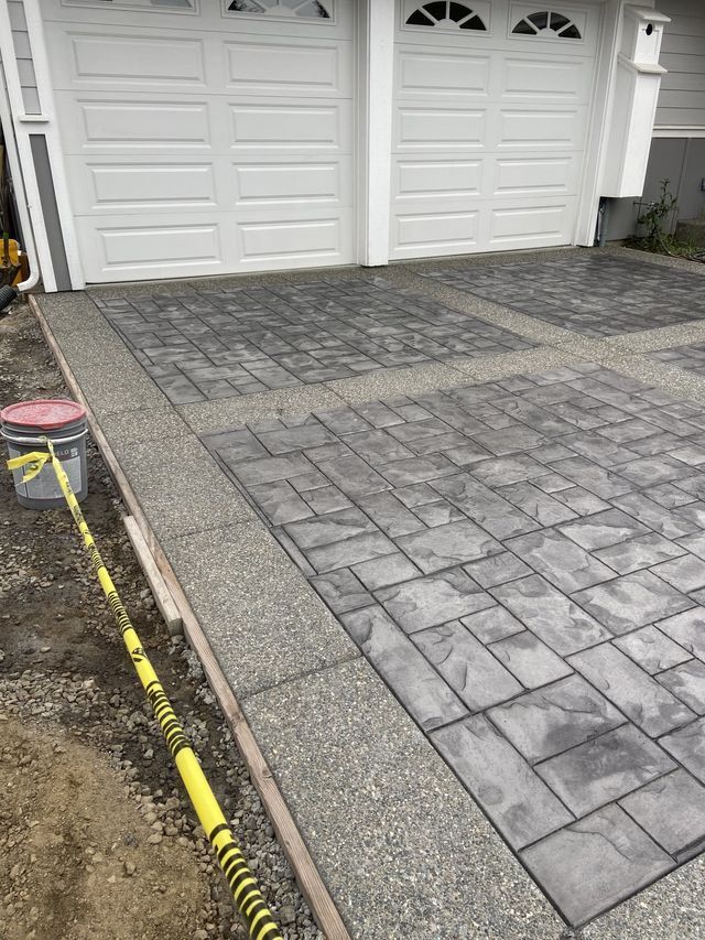 A concrete driveway is being installed in front of a garage.