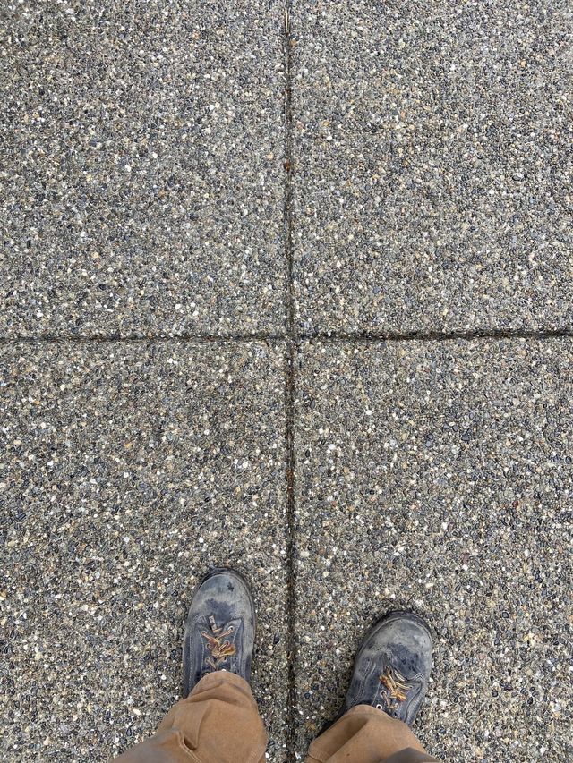 A person 's feet are standing on a tiled floor.