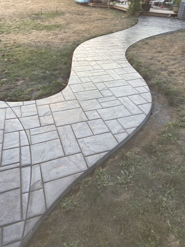 A concrete walkway going through a grassy area.