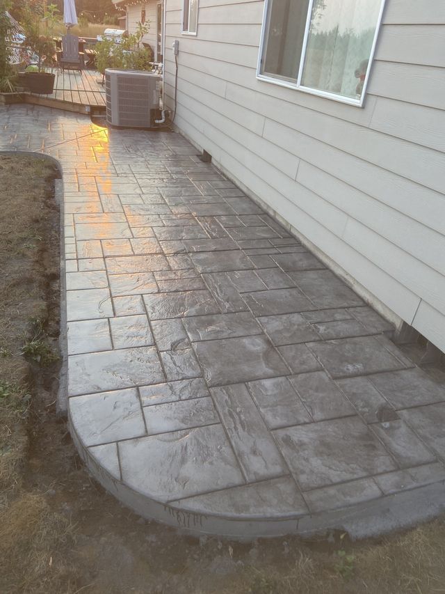 A concrete walkway next to a house with a window.