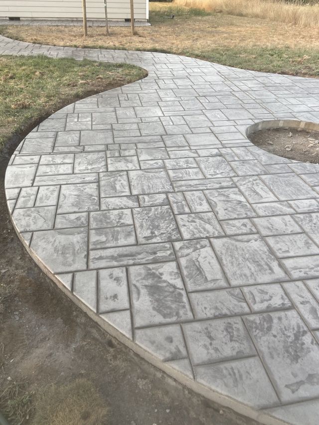 A concrete walkway with a fire pit in the middle of it.