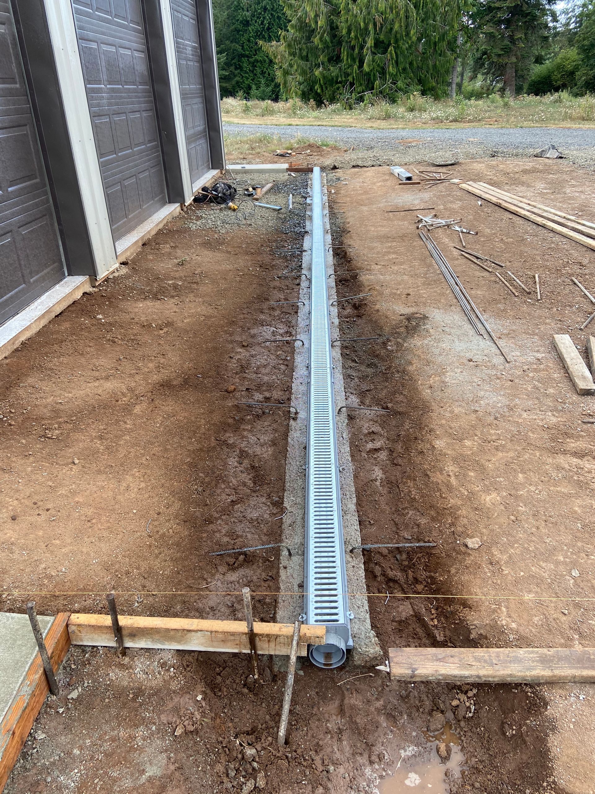 A drain is being installed in the dirt next to a building.