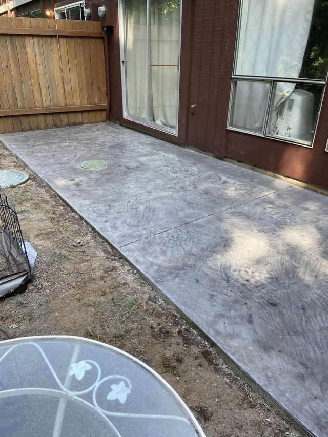 A concrete walkway leading to a house with a table in the foreground.
