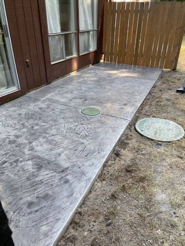 A concrete walkway leading to a house with a wooden fence.