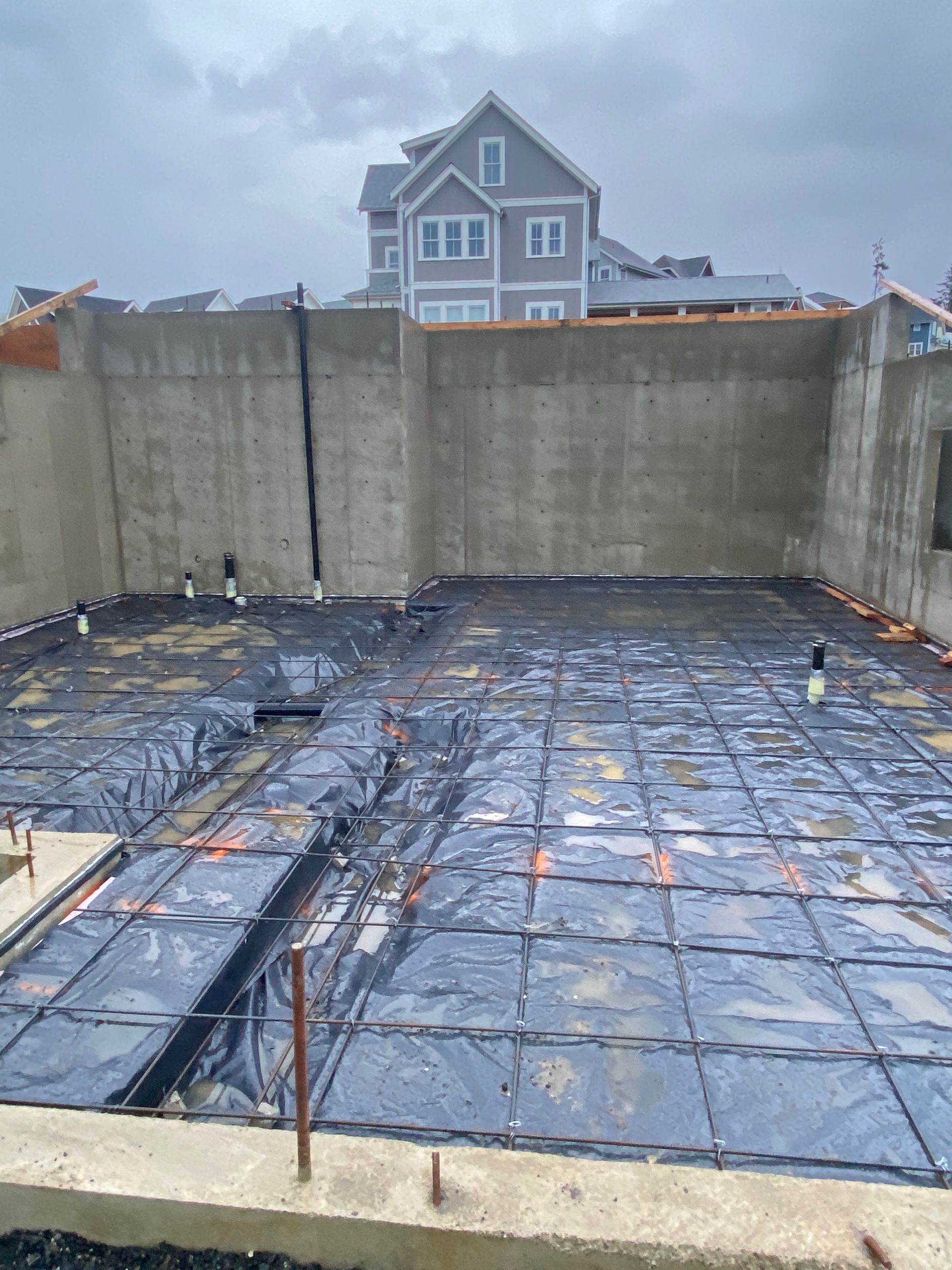 A concrete floor with a house in the background is being built.