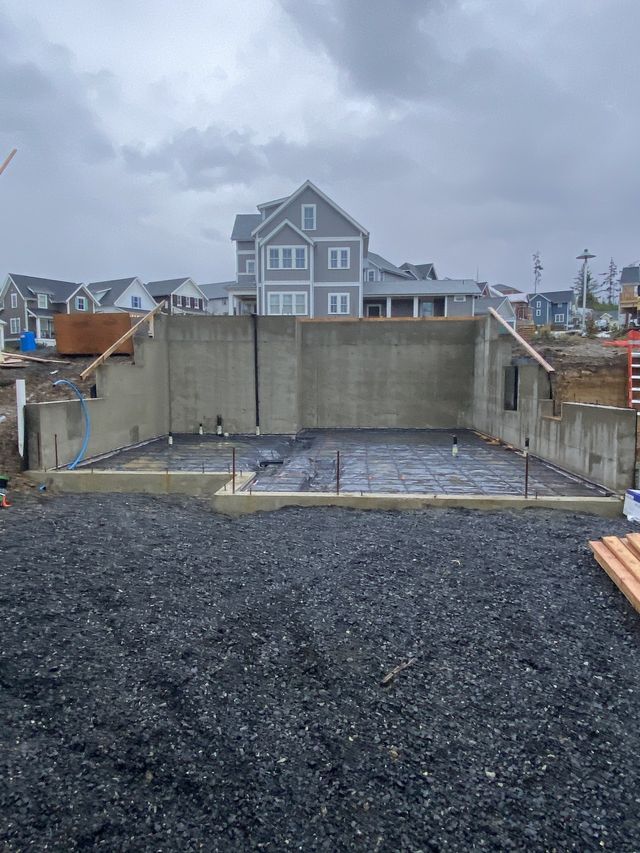 A large concrete wall is being built in front of a house.