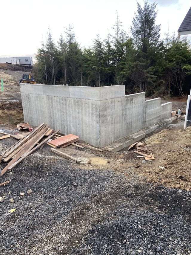 A large concrete wall is being built in the middle of a dirt field.