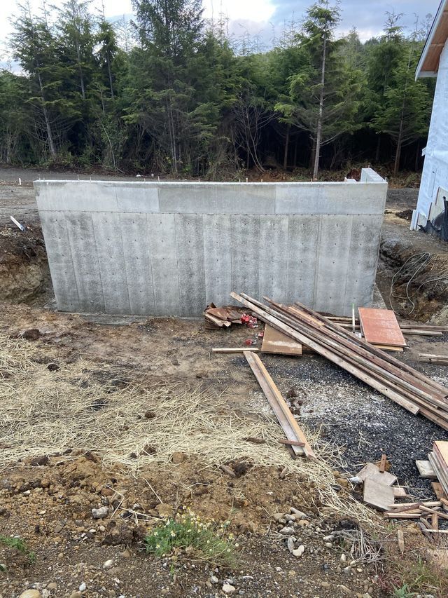 A large concrete wall is being built in the middle of a dirt field.