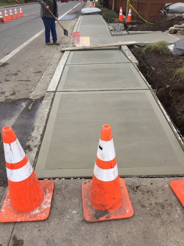 Two orange and white traffic cones on a sidewalk