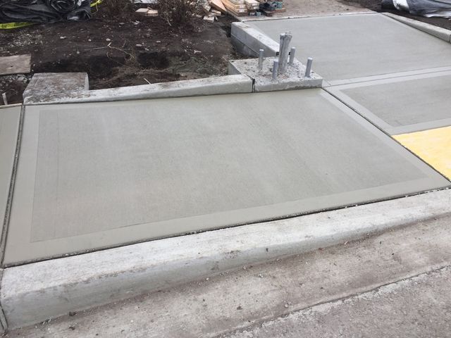 A concrete walkway with a yellow curb is being built