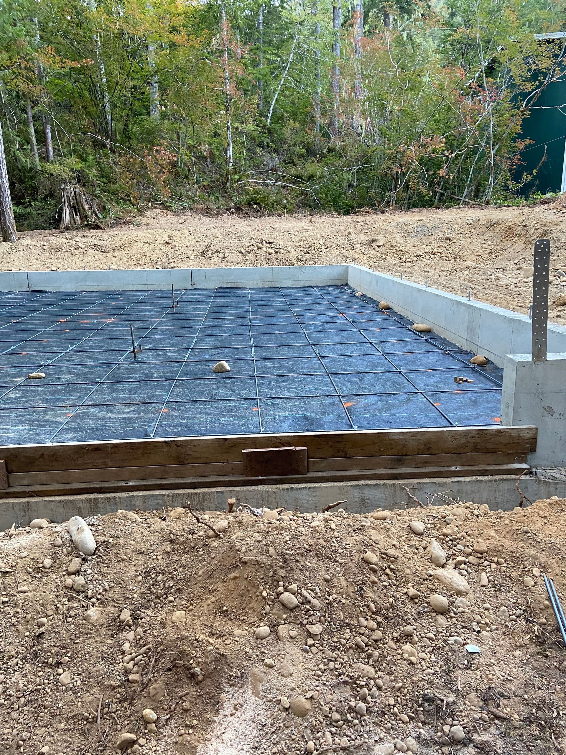 A concrete base for a house is being built in the woods.