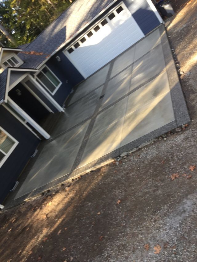 A concrete driveway in front of a blue house
